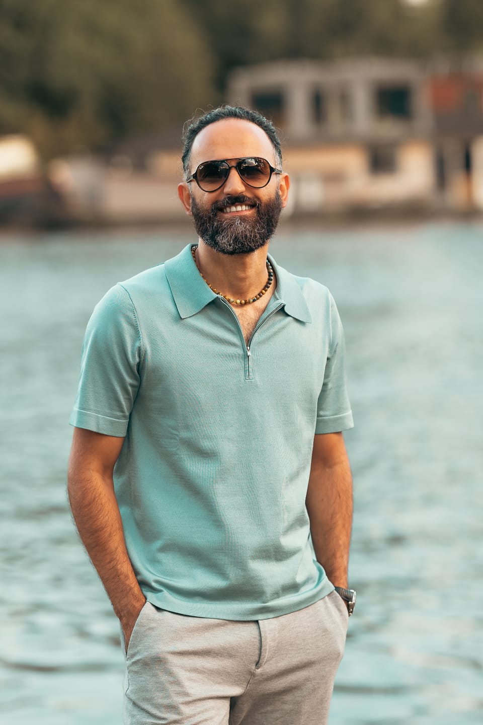 A portrait of photographer Peyman Shojaei standing by the water at dusk