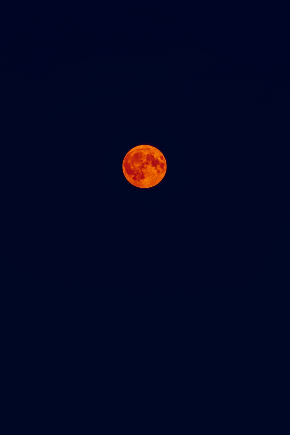 A deep red blood moon hanging in a dark night sky.