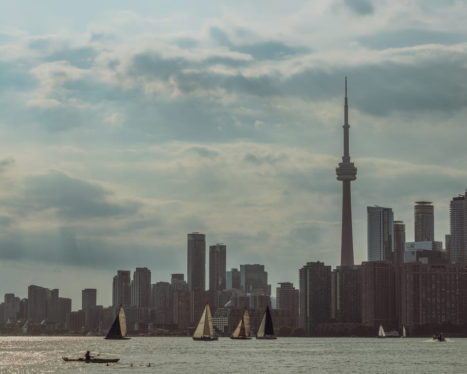 The Toronto skyline and CN Tower seen across the lake beneath heavy clouds.